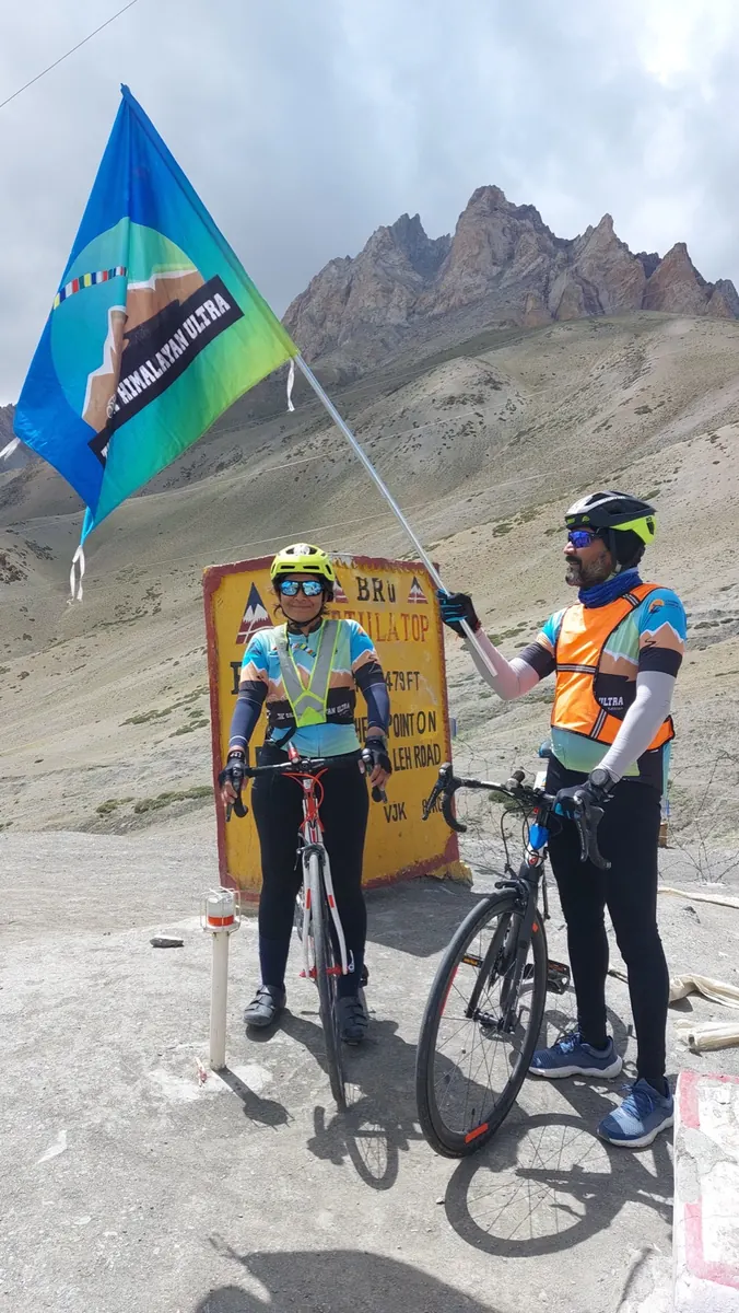 Sudhakar and Niharika at a Himalayan pass, a race flag flying