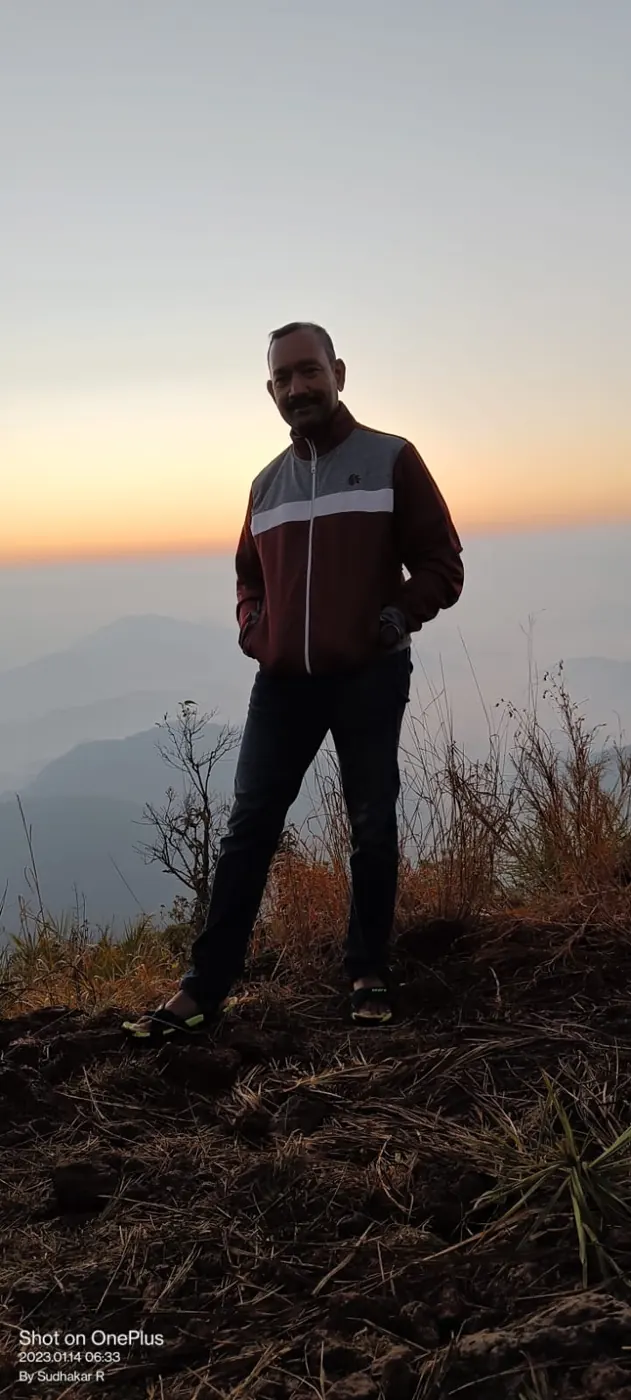 Sudhakar standing on a hilltop at sunrise, in silhouette